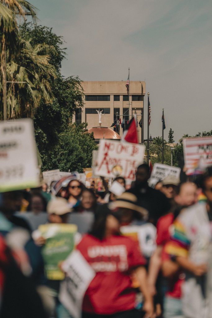Wide angle shot of protest march with Arizona State Capitol Building in focus behind the group. The people are out of focus.