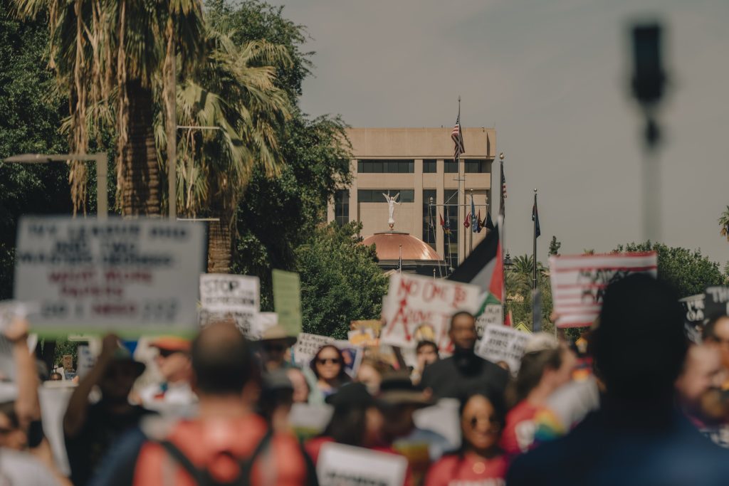Wide angle shot of protest march with Arizona State Capitol Building in focus behind the group. The people are out of focus.