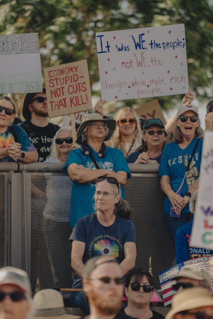 Protest gathering at Arizona State Capitol. Shows heads of people on ground, and then people behind fence about five feet above lower ground.