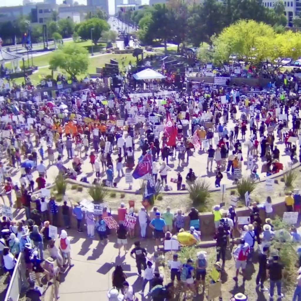 High up view of protest at the Arizona State Capitol. Average color of cloud is very purple.