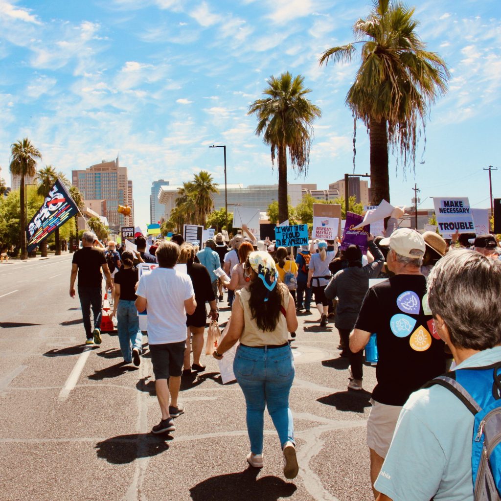Back view of protest march on Washington Street towards downtown Phoenix. About a dozen signs visible.