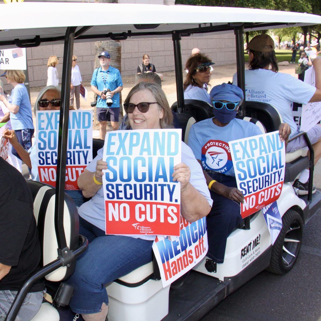 Protestors on a golf cart holding signs that say "Expand social security." "No cuts."